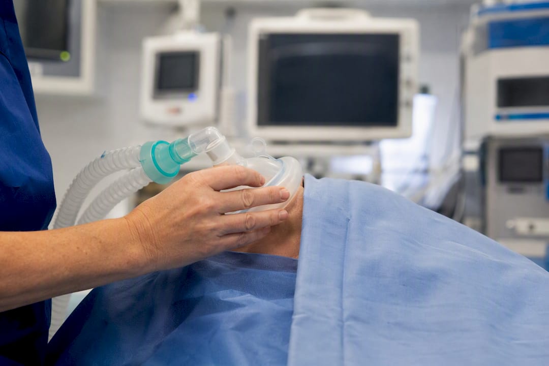 Mano sujetando la mascarilla de sedación cerca del rostro del paciente