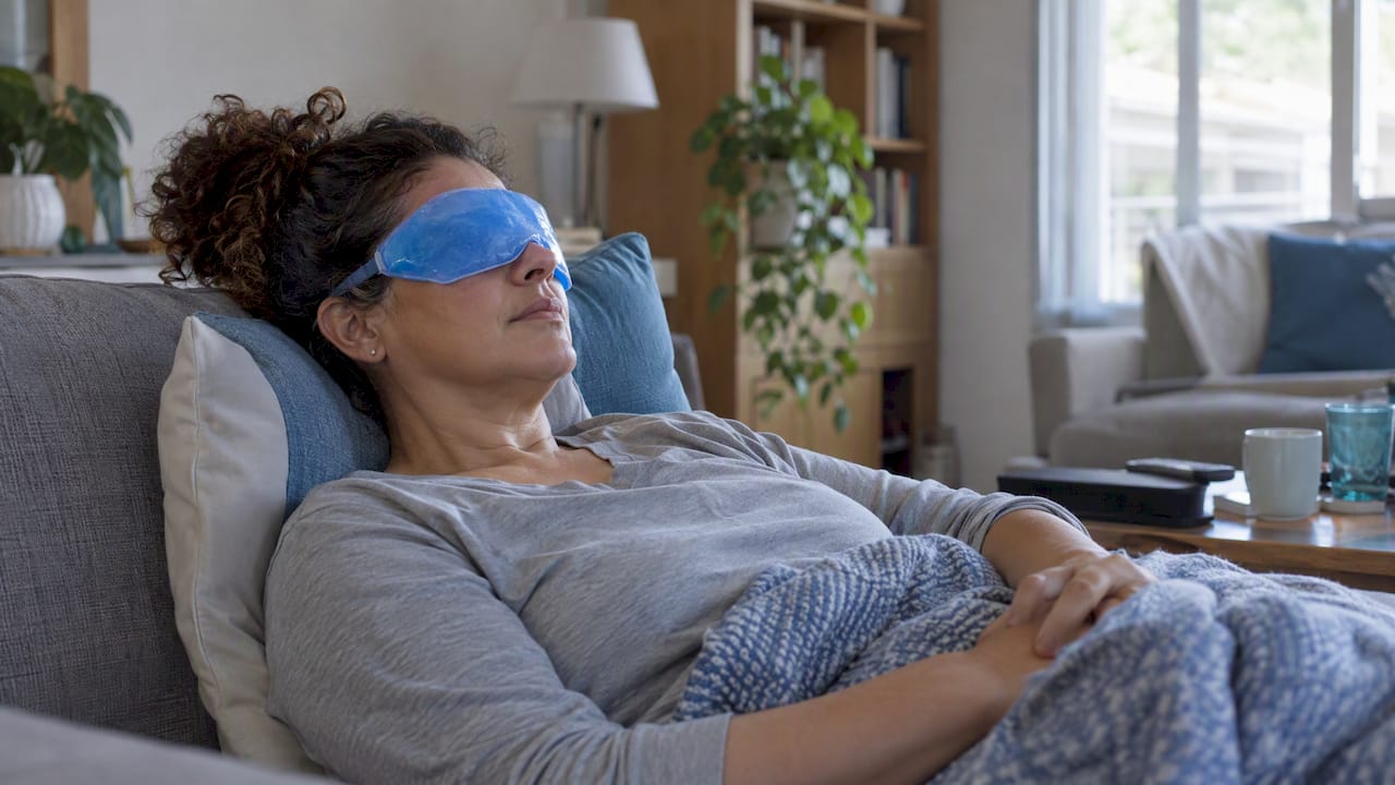 Mujer se relaja con una compresa fría sobre los ojos